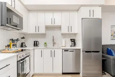 a kitchen with white cabinets and a stainless steel refrigerator at Modern High Rise King bed Condo with Private Balcony in Kitchener
