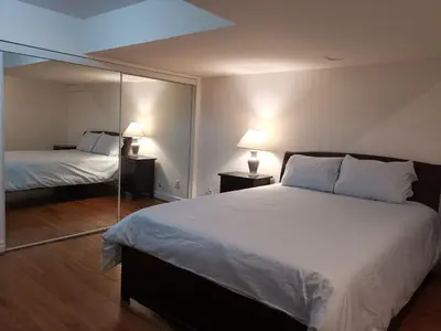 a bedroom with a large bed and a mirror at Cozy Private Rooms in Basement in Richmond Hill