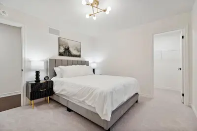 a white bedroom with a large bed and a chandelier at Luxury Vacation Home Near Lake Pool Table in Barrie