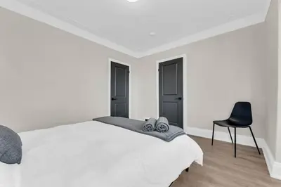 a bedroom with a white bed and a black chair at RentX 3Bed Cozy Home - Hospital GO 2ParkingWi-Fi in Hamilton