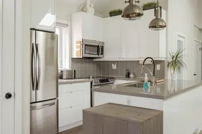 a kitchen with white cabinets and a stainless steel refrigerator at Lonborough Ave Upstairs in Toronto