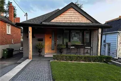 a house with a porch with a table and chairs at Lonborough Ave Upstairs in Toronto
