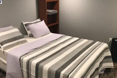 a bedroom with a bed with a striped blanket at Affordable 2BR Family Friendly Basement Apt in Bowmanville