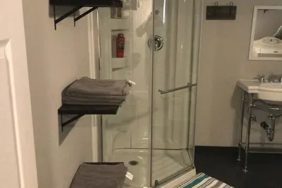 a bathroom with a shower and a sink and towels at Affordable 2BR Family Friendly Basement Apt in Bowmanville