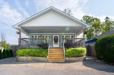 a small white house with a porch and stairs at Nancy by the Bay Wasaga Beach in Wasaga Beach