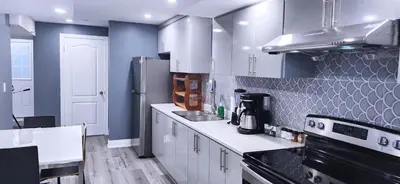 a kitchen with white cabinets and a black refrigerator at Garden Avenue Homes Free Parking in Brantford