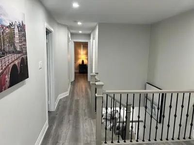 a hallway with white walls and stairs with a painting at Treasure Haven Near Tourism Barrie in Barrie