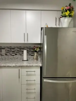 a kitchen with white cabinets and a stainless steel refrigerator at Toronto Midtown Room with Queen Bed in Toronto