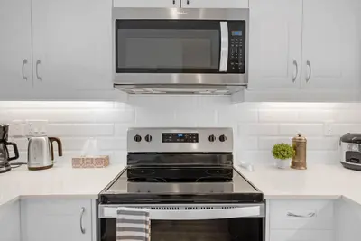 a kitchen with a stove and a microwave at Designer Yorkdale 2BR Townhouse, Private Patio, Parking in Toronto