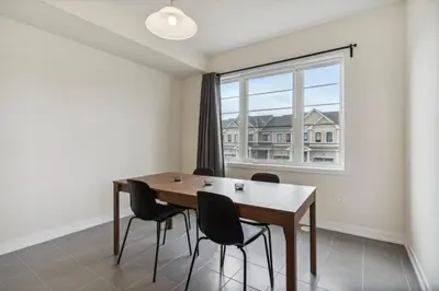a dining room with a table and chairs and a window at A Brand New 4BR Townhouse in Thorold Retreat in Thorold