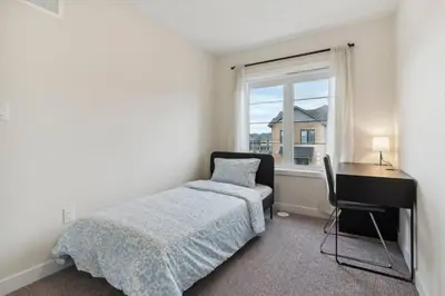 a bedroom with a bed and a desk and a window at A Brand New 4BR Townhouse in Thorold Retreat in Thorold