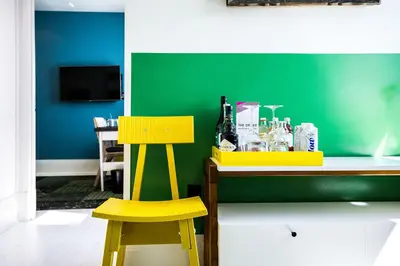 a table with two yellow chairs and a green wall at Drake Devonshire and Motor Inn in Wellington