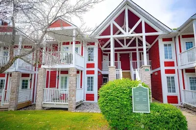 a red and white house with a sign in front of it at Jacuzzi Suite with King bed, full kitchen in Shanty Bay