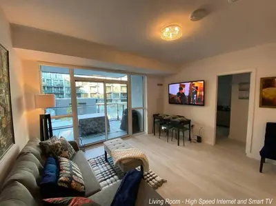 a living room with a couch and a tv and a table at Beautiful Condo, 2 Bedrooms and a Den in Friday Harbour Resort! in Innisfil