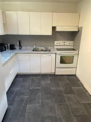 a kitchen with white cabinets and a stove and a sink at Quaint and Cozy Haven in Toronto