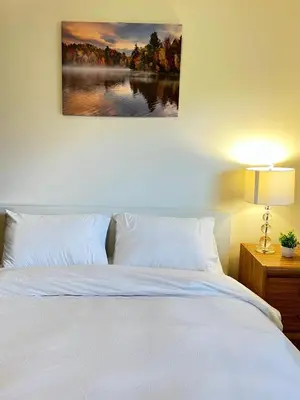 a bedroom with a white bed and a painting on the wall at Entire Cozy House in Thorold in Thorold