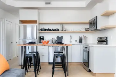 a kitchen with white cabinets and bar stools at Large Victorian Sleeps 6 by UofT in Toronto