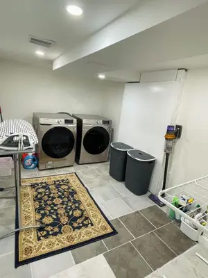 a laundry room with two washing machines and two trash cans at New Cosy bright and Spacious Apartment in East Gwillimbury