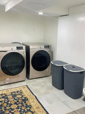 two washing machines and two trash cans in a room at New Cosy bright and Spacious Apartment in East Gwillimbury