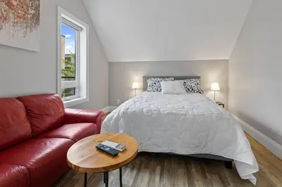 a bedroom with a bed and a red couch at ENTIRE BACHELOR UNIT EN-SUITE ACROSS FROM GOOGLE - br4 in Kitchener