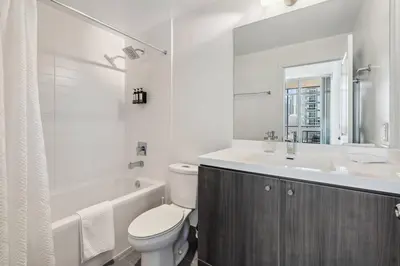 a white bathroom with a toilet and a tub and a sink at Amazing View 2BR St Lawrence Market Condo, Downtown Toronto in Toronto