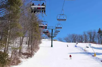 a group of people riding a ski lift in the snow at River Runs Through It in Belleville