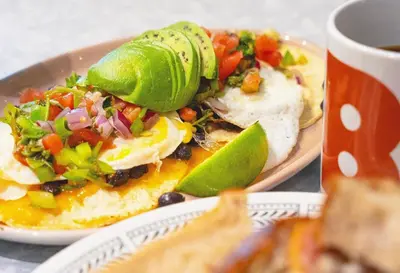 a plate of food with eggs and salsa and a cup of coffee at Big apartment by the Farmers market in Kitchener