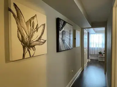 a hallway with paintings on the walls of a house at 2 bedroom rental apartment , 1 sofa bed, 2 car parking in Mississauga