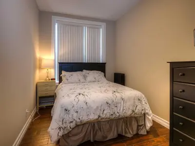 a bedroom with a bed and a dresser and a window at Western Hotel & Executive Suites in Guelph
