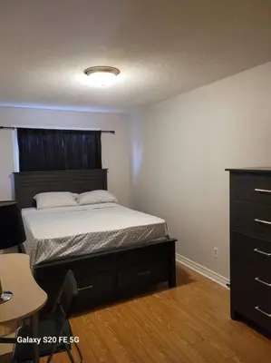 a bedroom with a bed and a dresser at Home away from home in Brampton