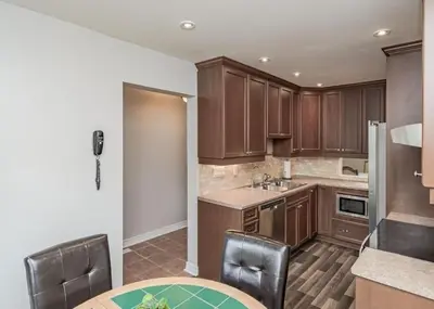 a kitchen with wooden cabinets and a table and chairs at Home away from home in Brampton