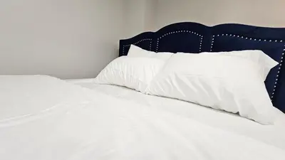 a bed with white sheets and pillows on it at Garden Ave Home 1mins to HWY 403 in Brantford
