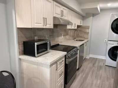 a kitchen with a microwave and a stove top oven at Rita's Kunjo - 2BR, 3BD, 2WR, Full Ktchn, Living in Whitby