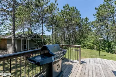 a grill on the deck of a house at Cozy cottage on a private beach -Georgian Bay in Tiny
