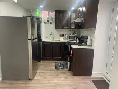 a kitchen with wooden cabinets and a black refrigerator at 2 Bedroom Guest Apartment with Separate Entrance in Brampton