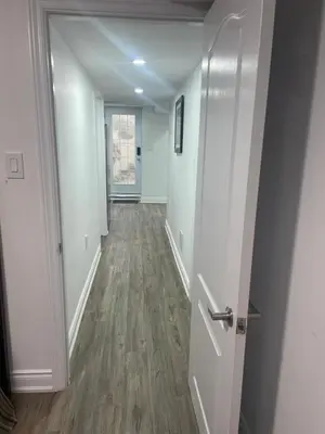 an empty hallway with a door and wooden floors at 2 Bedroom Guest Apartment with Separate Entrance in Brampton