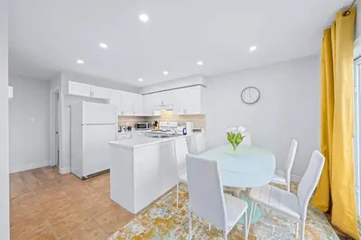 a white kitchen with a table and chairs at Stylish and Cozy 4 bedroom House in Barrie