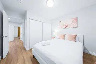 a white bedroom with a large white bed with pink pillows at Stylish and Cozy 4 bedroom House in Barrie