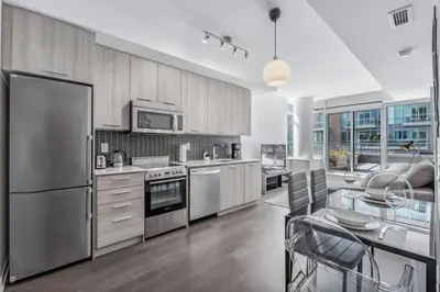 a kitchen with stainless steel appliances and a table with chairs at Stylish 2BR Urban Escape, BBQ, Private Terrace in Toronto