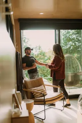 a man and a woman shaking hands in a room at Aux Box Muskoka Modern Muskoka Bunkie in Huntsville