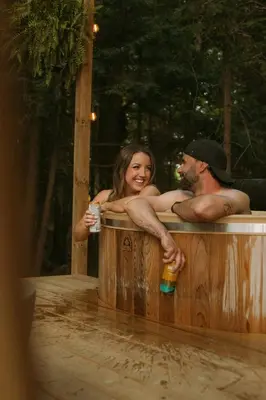 a man and a woman sitting in a hot tub at Aux Box Muskoka Modern Muskoka Bunkie in Huntsville