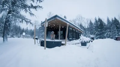 a woman standing in the window of a house in the snow at Wolegib Waterfront Retreat in Muskoka in Huntsville