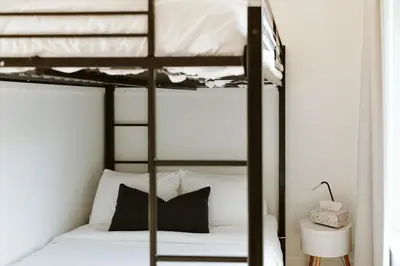 a bedroom with two bunk beds with white sheets at Wolegib Waterfront Retreat in Muskoka in Huntsville