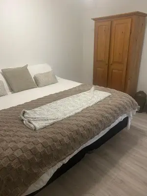 a bedroom with a bed and a wooden cabinet at Treetop Suite in Haliburton