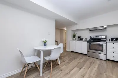 a kitchen with a white table and chairs in a room at Modern & Cozy 1 Bedroom with fast Wi-Fi, BBQ & Patio in Barrie