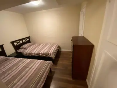 a small room with two beds and a dresser at Sunnys Home Stays 1 Bedroom Bath & Kitchenette Toronto Mississauga At Erin Mills With Pvt Entrance in Mississauga