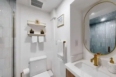 a white bathroom with a sink and a mirror at Fresh and Modern Guest Suite in Toronto