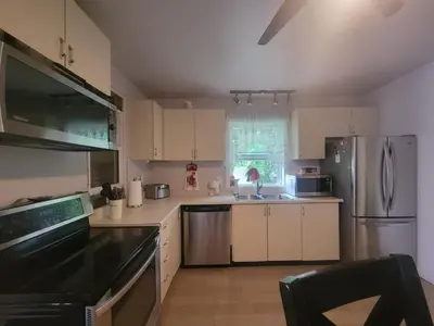 a kitchen with white cabinets and stainless steel appliances at ARCA Cozy Cabin-Innisfil Beach in Innisfil