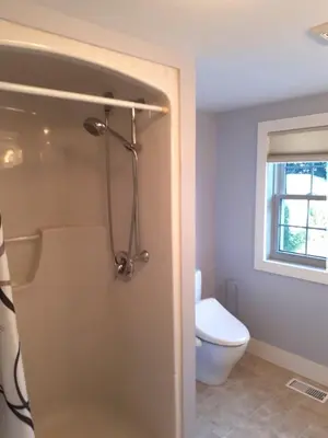 a bathroom with a shower with a toilet and a window at Sakura Cottage - Serenity on PEC Waterfront in Wellington