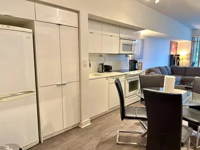a kitchen and a living room with a table and chairs at Comfy 1Bdrm den 2Baths with 3 real beds plus parking in Toronto